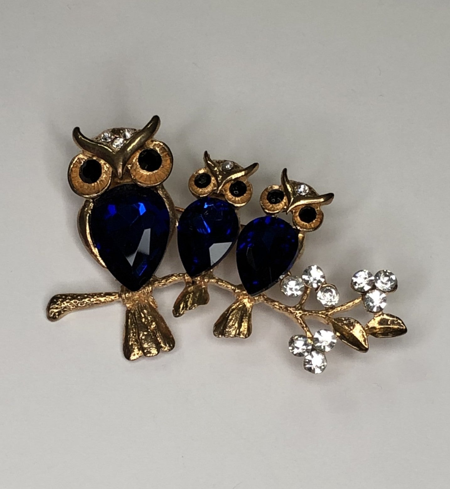 Three blue owls perched on branch brooch at erika