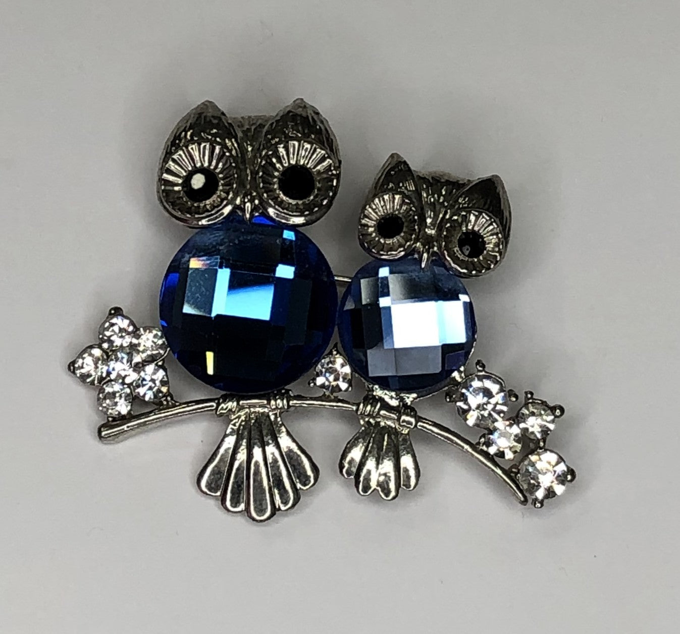 Two silver and blue stone owls perched on branch brooch at erika