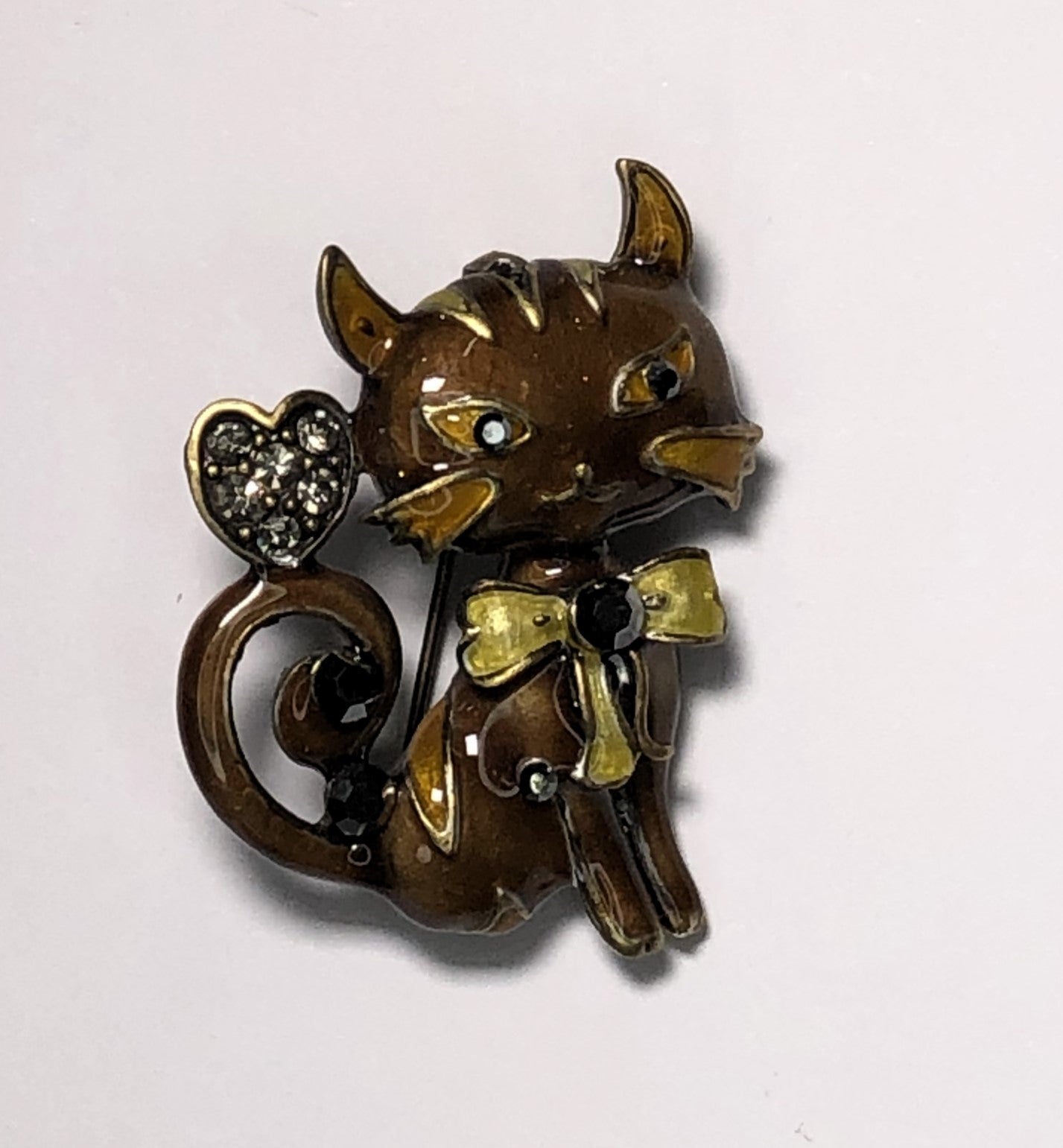 Enameled brown and tan cat with jewelled heart on tail and yellow bow brooch at erika