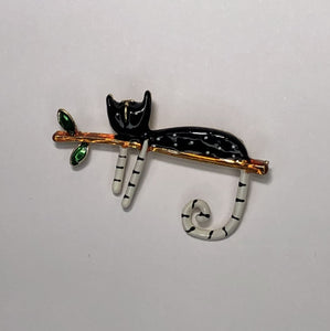 Black and white enameled finish cat relaxing on branch brooch at erika