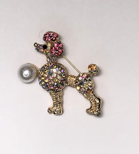 Gold poodle dog with pink ears and pearl brooch at erika