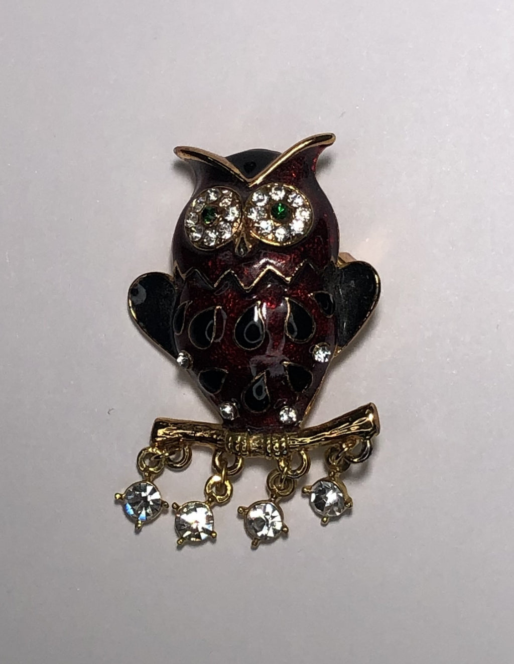 Red enameled owl with green eye and hanging diamantes perched on branch brooch at erika